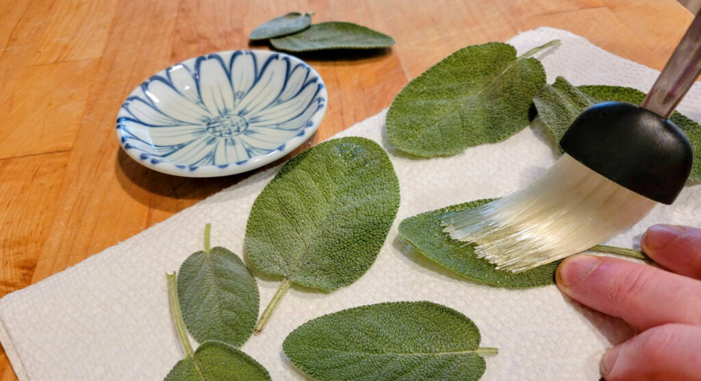 Coating sage with olive oil with a brush on a butcher block