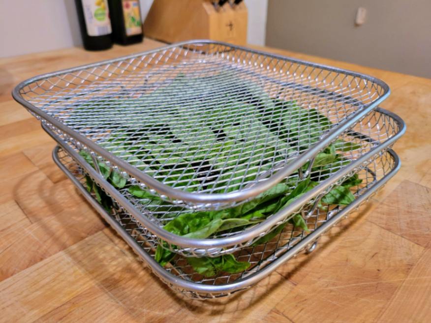 Basil in air fryer trays before drying