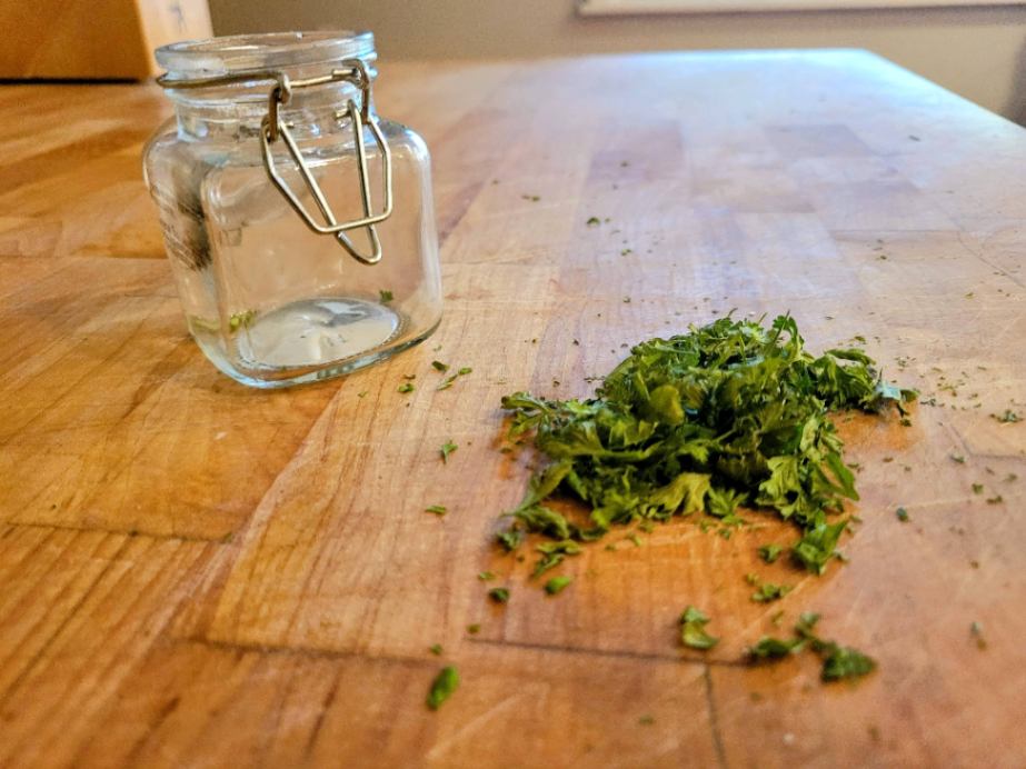 Dried parsley on butcher block with class container