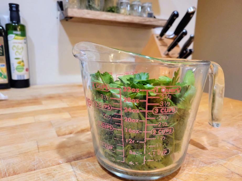 bunch of Italian parsley measuring 4 cups in a large measuring cup on a butcher block counter